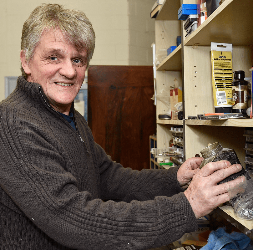 man putting an item onto wooden shelf